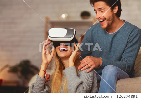 Excited Couple Using Virtual Reality Glasses Playing Videogame Having Fun At Home. Selective Focus Excited Couple Using Virtual Reality Glasses Playing Videogame Having Fun At Home. Selective Focus 126274891