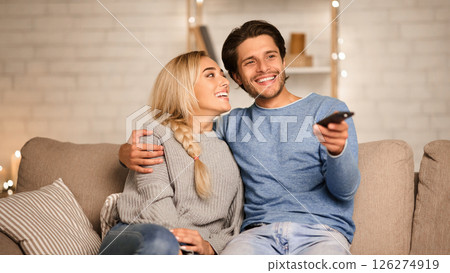 Cute couple in love watching TV, enjoying cozy atmosphere at home, free space Cute couple in love watching TV, enjoying cozy atmosphere at home, free space 126274919