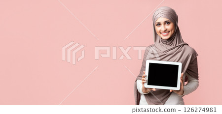 Muslim girl in headscarf demonstrating digital tablet with black screen over pink background in studio, empty space Muslim girl in headscarf demonstrating digital tablet with black screen over pink background in studio, empty space 126274981