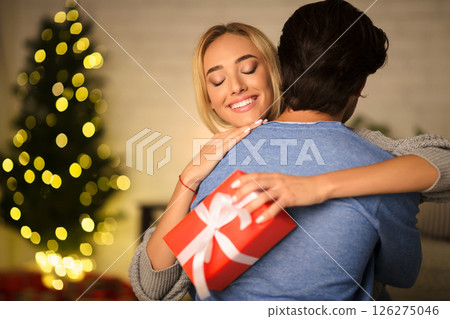 Christmas time. Happy wife embracing man, being thankful for present 126275046
