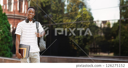Happy smiling african american student guy with backpack and workbooks over university background, looking at camera and smiling 126275152