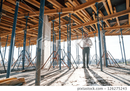 Beautiful sunlight. Walking with plan in hands. Man is working on the construction site at daytime 126275243