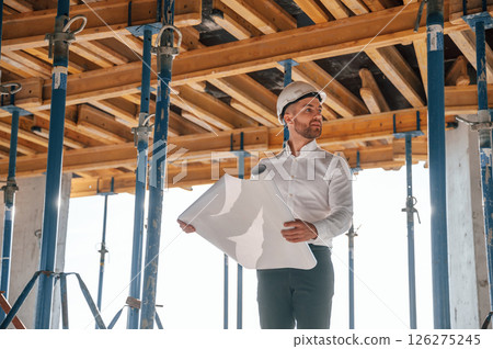 Beautiful sunlight. Walking with plan in hands. Man is working on the construction site at daytime 126275245