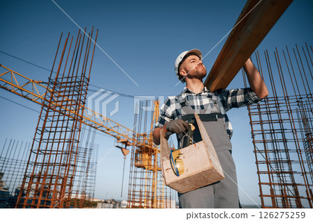 Moving wooden plank. Man is working on the construction site at daytime 126275259