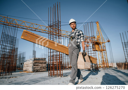 With toolbox and wooden plank. Man is working on the construction site at daytime With toolbox and wooden plank. Man is working on the construction site at daytime 126275270