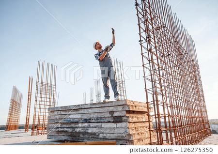 Communicating with other people. Man is working on the construction site at daytime 126275350