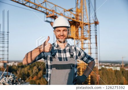 Standing and smiling. Man is working on the construction site at daytime Standing and smiling. Man is working on the construction site at daytime 126275392