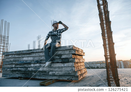 Sitting and looking to the side. Man is working on the construction site at daytime 126275421