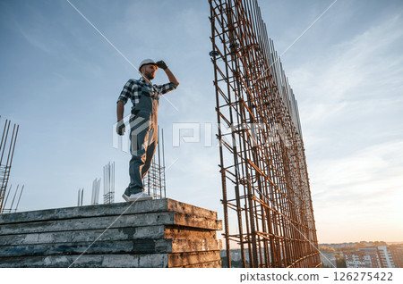 Near big metal objects. Man is working on the construction site at daytime Near big metal objects. Man is working on the construction site at daytime 126275422