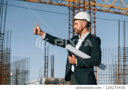 Showing thumb up. Businessman in formal clothes is on the construction site at daytime 126275438