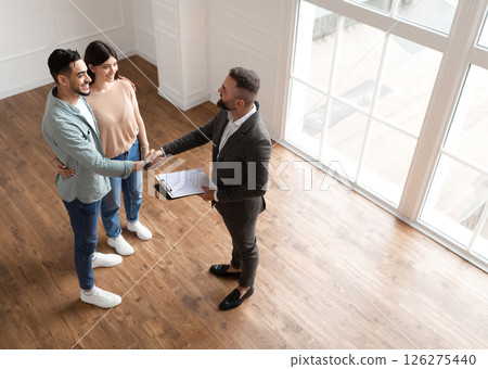Successful Deal Concept. Above Top High Angle View Of Millennial Couple Buying New Apartment, Shaking Hands With Professional Real Estate Agent. Smiling Manager Showing Flat To Happy Young Family 126275440