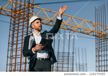 Giving orders by hand gesture. Businessman in formal clothes is on the construction site at daytime 126275497