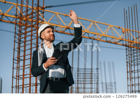 Giving orders by hand gesture. Businessman in formal clothes is on the construction site at daytime 126275499