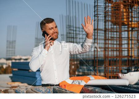Businessman in formal clothes is on the construction site at daytime Businessman in formal clothes is on the construction site at daytime 126275523