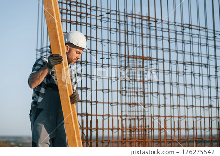 Standing near steel frame. Man is working on the construction site at daytime Standing near steel frame. Man is working on the construction site at daytime 126275542