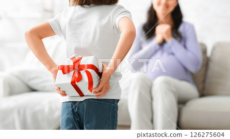 Back view of little girl with gift box for her pregnant excited mom, daughter greeting mother with Mother's Day 126275604