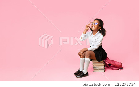 Idea Or Question. African American Schoolgirl Pointing Finger Up Sitting On Book Stack Over Yellow Studio Background. Copy Space 126275734