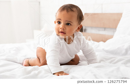 Cute African Little Baby Boy Crawling On Bed Looking Aside Posing In Bedroom At Home. Full Length Portrait Shot Of Adorable Toddler Kid. Sweet Childhood Moments, Child Care Concept 126275794