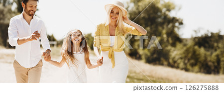 Happy parents walking with daughter, holding hands and spending time together in countryside Happy parents walking with daughter, holding hands and spending time together in countryside 126275888