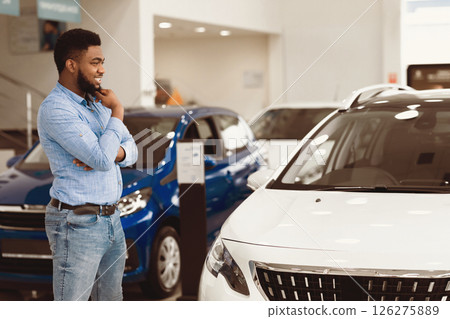 Buying Car. Cheerful African American Man Looking At Auto Standing In Dealership Showroom. Emtpy Space For Text Buying Car. Cheerful African American Man Looking At Auto Standing In Dealership Showroom. Emtpy Space For Text 126275889