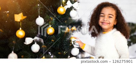 Christmas preparations. Adorable little african girl decorating xmas tree at home Christmas preparations. Adorable little african girl decorating xmas tree at home 126275901