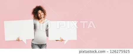 African-american pregnant lady holding two blank speech bubbles near belly, pink background African-american pregnant lady holding two blank speech bubbles near belly, pink background 126275925