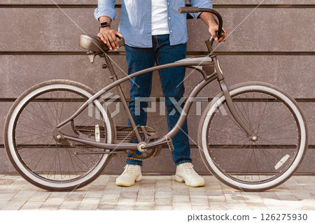 Unrecognizable Afro Man Holding Bicycle With Stylish Design, Standing Over Grey Urban Wall, Cropped Image, Closeup 126275930