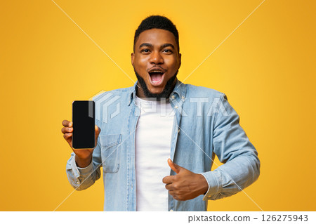 Wow, amazing app. Surprised african man holding smartphone with black screen and showing thumb up, yellow background with free space Wow, amazing app. Surprised african man holding smartphone with black screen and showing thumb up, yellow background with free space 126275943