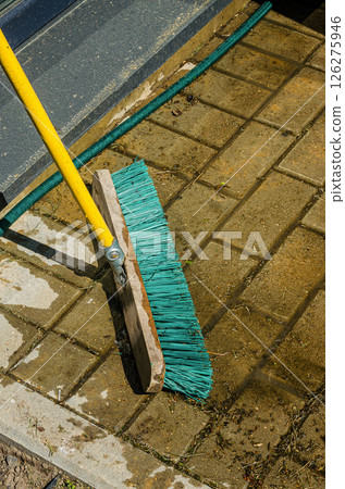 Outdoor patio cleaning process using broom and hose in bright sunlight for effective results. High quality photo Outdoor patio cleaning process using broom and hose in bright sunlight for effective results. High quality photo 126275946