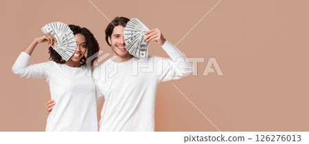 Successful Investment Concept. Happy young interracial couple covering eyes with dollar cash, posing together on yellow background Successful Investment Concept. Happy young interracial couple covering eyes with dollar cash, posing together on yellow background 126276013