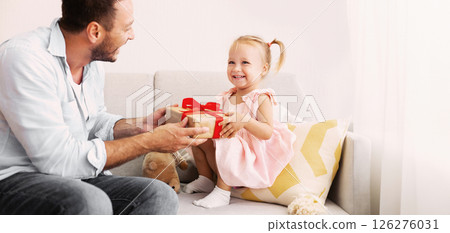 Birthday Present. Happy loving family sitting on the couch and holding gift box with red bow 126276031