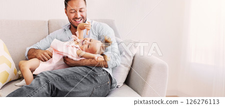 Happy Family. Cheerful dad tickling little girl, happy daughter is laughing, sitting on sofa in living room 126276113