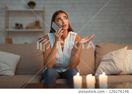 Electrical Issue. Girl Calling Electrician Service Via Mobile Phone Sitting On Couch In Dark Room Lit By Candles. Selective Focus 126276146