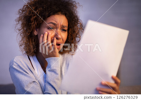 Disappointed woman reading letter of break up from boyfriend, girl covering mouth with hand Disappointed woman reading letter of break up from boyfriend, girl covering mouth with hand 126276329
