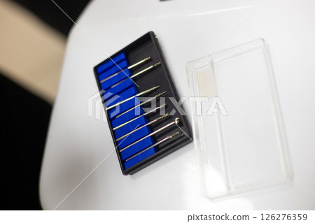 Veterinary instruments set featuring organized burs in a black box with blue foam, placed on a white table within a clinic or hospital environment, ready for animal care and treatment. 126276359