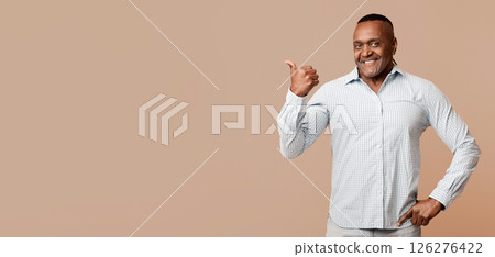 Friendly middle aged african man pointing aside at free space, orange panorama background Friendly middle aged african man pointing aside at free space, orange panorama background 126276422