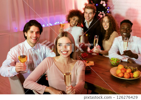 New Year Dinner. Happy Friends Having Home Party Holding Glasses Smiling At Camera Celebrating Christmas Holidays Sitting At Table Indoor New Year Dinner. Happy Friends Having Home Party Holding Glasses Smiling At Camera Celebrating Christmas Holidays Sitting At Table Indoor 126276429