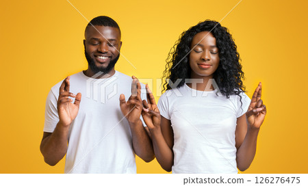 Let's Make Things Better. Young Cheerful African American Couple With Closed Eyes And Crossed Fingers, yellow background 126276475