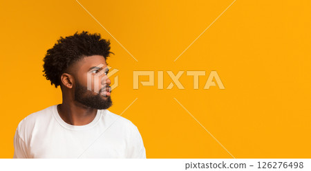 Skeptical young african american man looking aside at free space on orange background 126276498