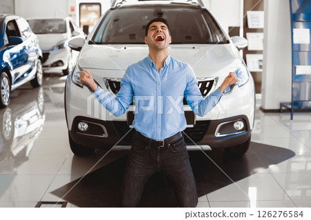 Yes, That's My New Car. Elated excited man kneeling in front of his auto in dealership office, making winner gesture 126276584
