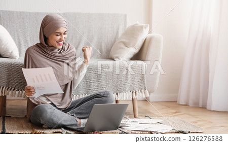Joyful Muslim Woman Celebrating Business Success While Working With Papers And Laptop At Home, Finished Importrant Project Joyful Muslim Woman Celebrating Business Success While Working With Papers And Laptop At Home, Finished Importrant Project 126276588
