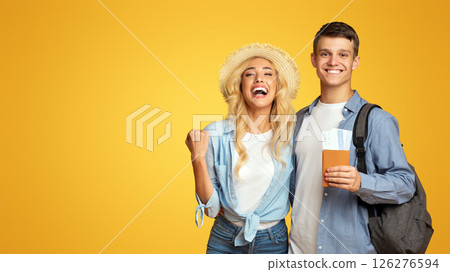 Getting visa. Joyful couple holding passport with flying tickets and celebrating success over yellow background with copy space 126276594
