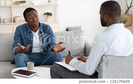 Stressed black man explaining his problems to psychologist at individual therapy session at office, copy space 126276609