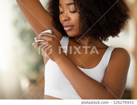 Beautiful black woman using epilator to remove unwanted hair from her armpit at home. Lovely African American lady doing domestic beauty procedure, taking care of her body indoors Beautiful black woman using epilator to remove unwanted hair from her armpit at home. Lovely African American lady doing domestic beauty procedure, taking care of her body indoors 126276933