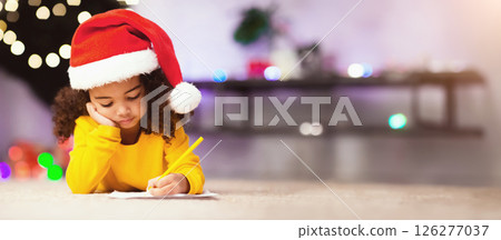Pretty african girl in Santa hat writing letter to Santa near christmas tree 126277037