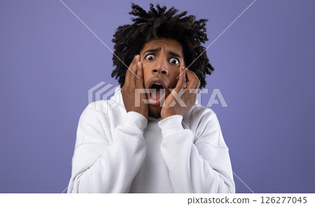 Black teen guy feeling scared, shouting in panic on violet studio background. Terrified African American teenager suffering from phobia, being scared or frightened. Negative human emotions concept Black teen guy feeling scared, shouting in panic on violet studio background. Terrified African American teenager suffering from phobia, being scared or frightened. Negative human emotions concept 126277045