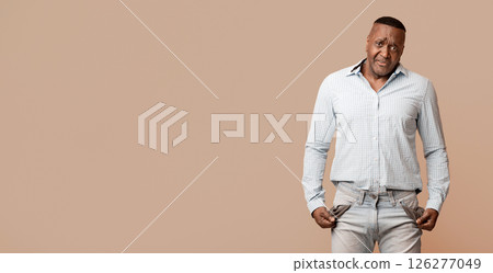 Coronacrisis concept. Sad mature african american man showing empty pockets, orange studio background Coronacrisis concept. Sad mature african american man showing empty pockets, orange studio background 126277049