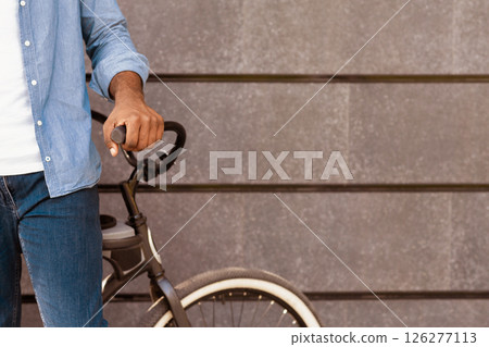Unrecognizable african american man standing near his bicycle against grey wall background, copy space 126277113