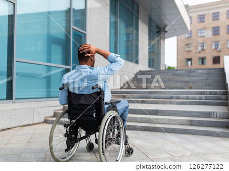 Problems with accessible environment for disabled people. Irritated impaired black man in wheelchair having no possibility to enter building without ramp, outdoors. Empty space Problems with accessible environment for disabled people. Irritated impaired black man in wheelchair having no possibility to enter building without ramp, outdoors. Empty space 126277122