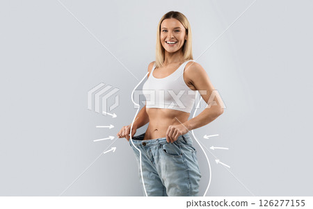 Cheery attractive slender middle aged blonde woman wearing huge jeans, showing results of diet, white body shape lines around happy slim lady, collage for slimming concept, copy space Cheery attractive slender middle aged blonde woman wearing huge jeans, showing results of diet, white body shape lines around happy slim lady, collage for slimming concept, copy space 126277155